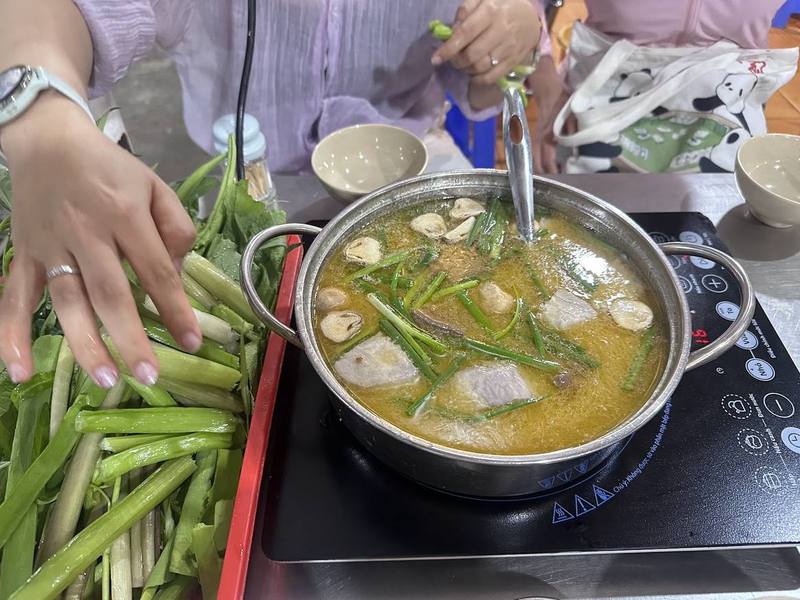 Nhúng rau vào nồi lẩu đang sôi